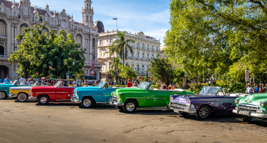 Salsa Dancing in Cuba: Colorful classic convertibles in yellow, red, blue, green, and purple are parked near classic buildings.