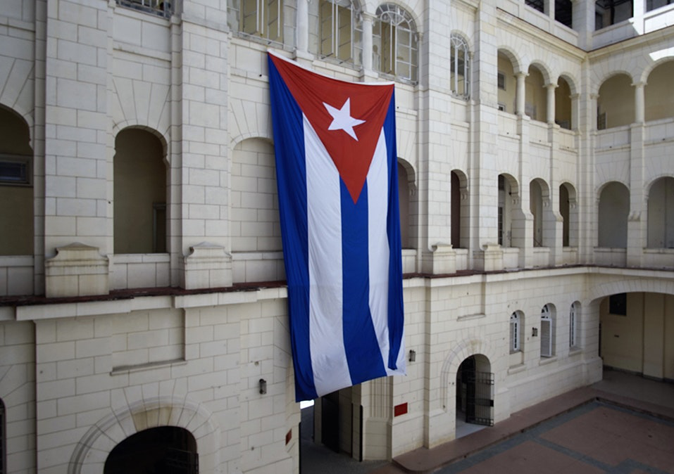 Salsa Dancing in Cuba: A oversized Cuban flags hangs in the central square of a building.